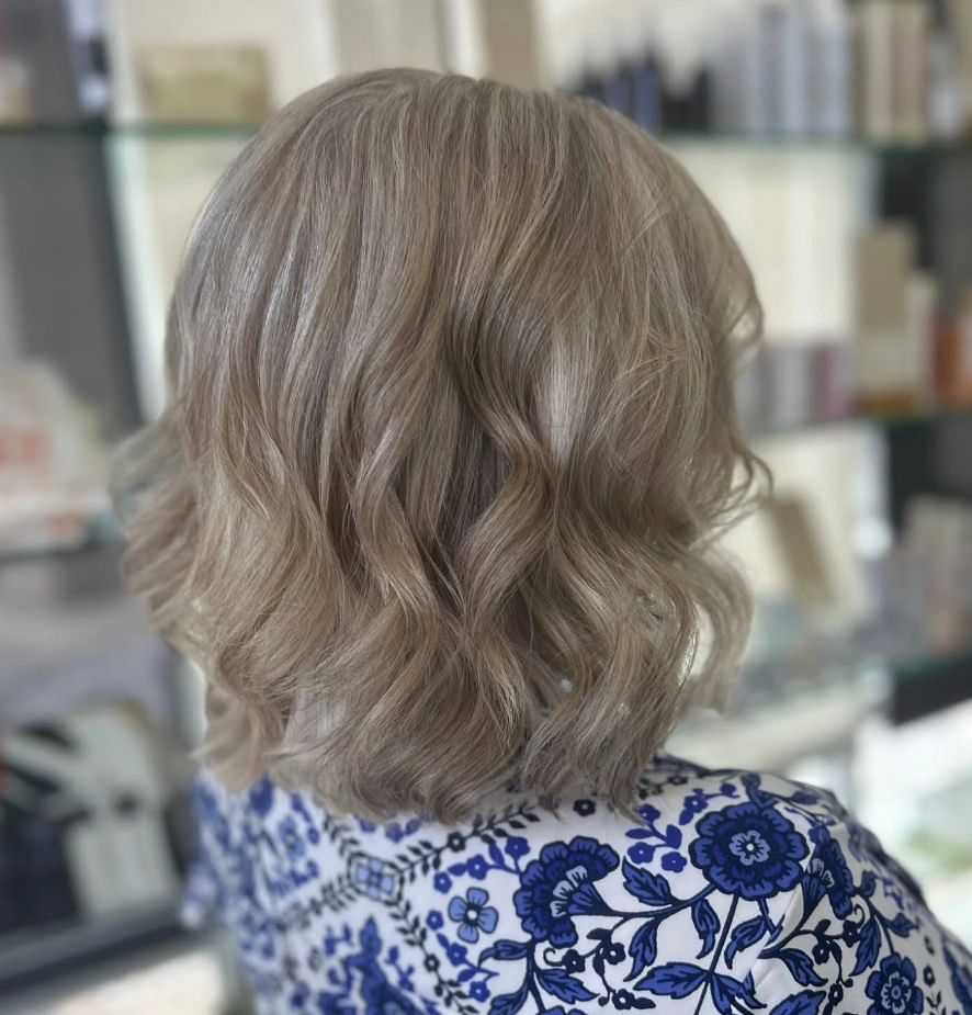 Short curly gray hairstyle on a person wearing a blue floral patterned top.