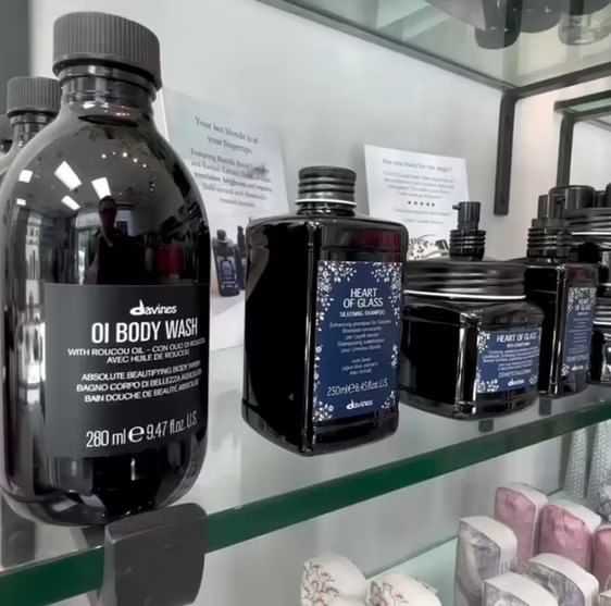 Bottles of Davines body wash and hair products displayed on a glass shelf in a store.