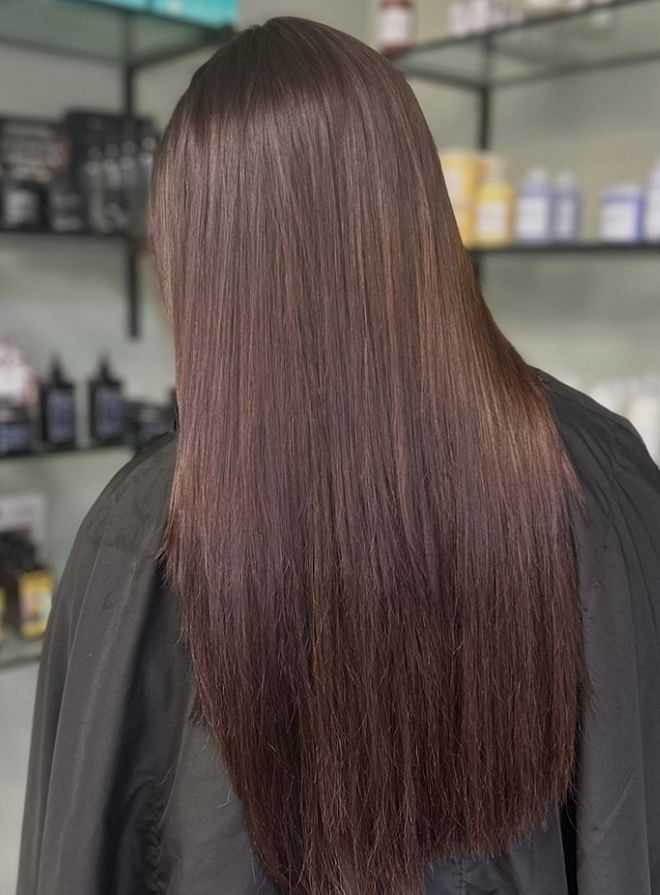 Smooth, shiny long brown hair with a sleek finish in a salon setting.