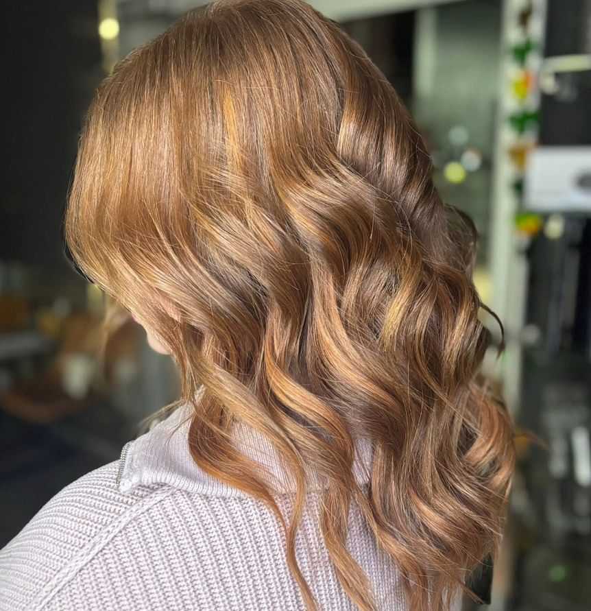 Curly auburn hair with soft highlights in a salon setting.